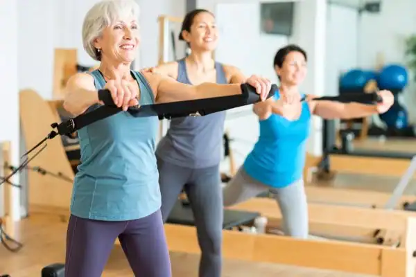 Toning Arms After 60: Empowering Womens Fitness Through Effective Weight Training 2 older woman doing weight training Leicestershire and resistance in the gym to tone upper arms