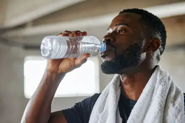 Image of man drinking water to improve hydration Leicestershire after work out.